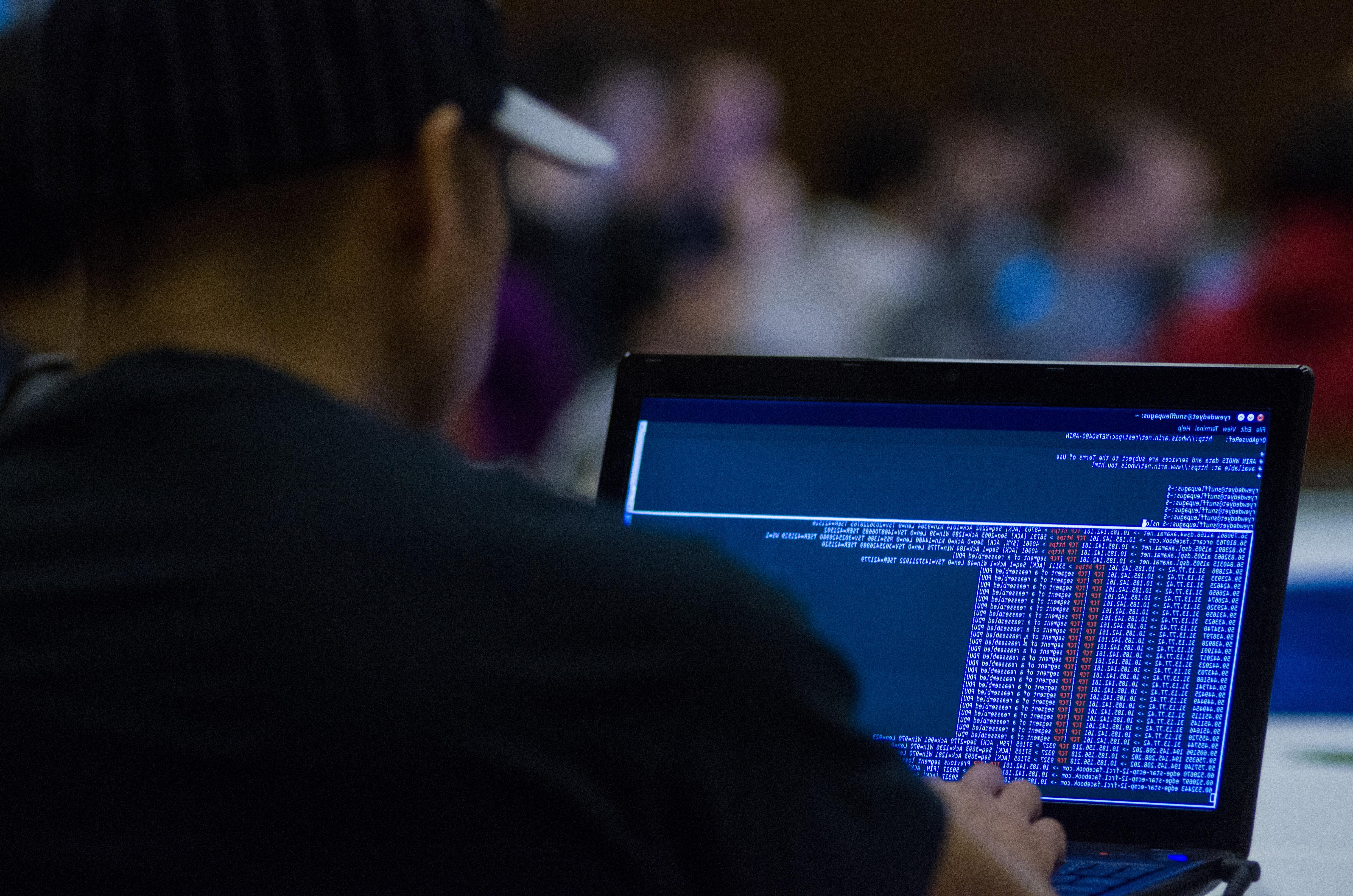  A picture of a man typing code into a laptop computer. 