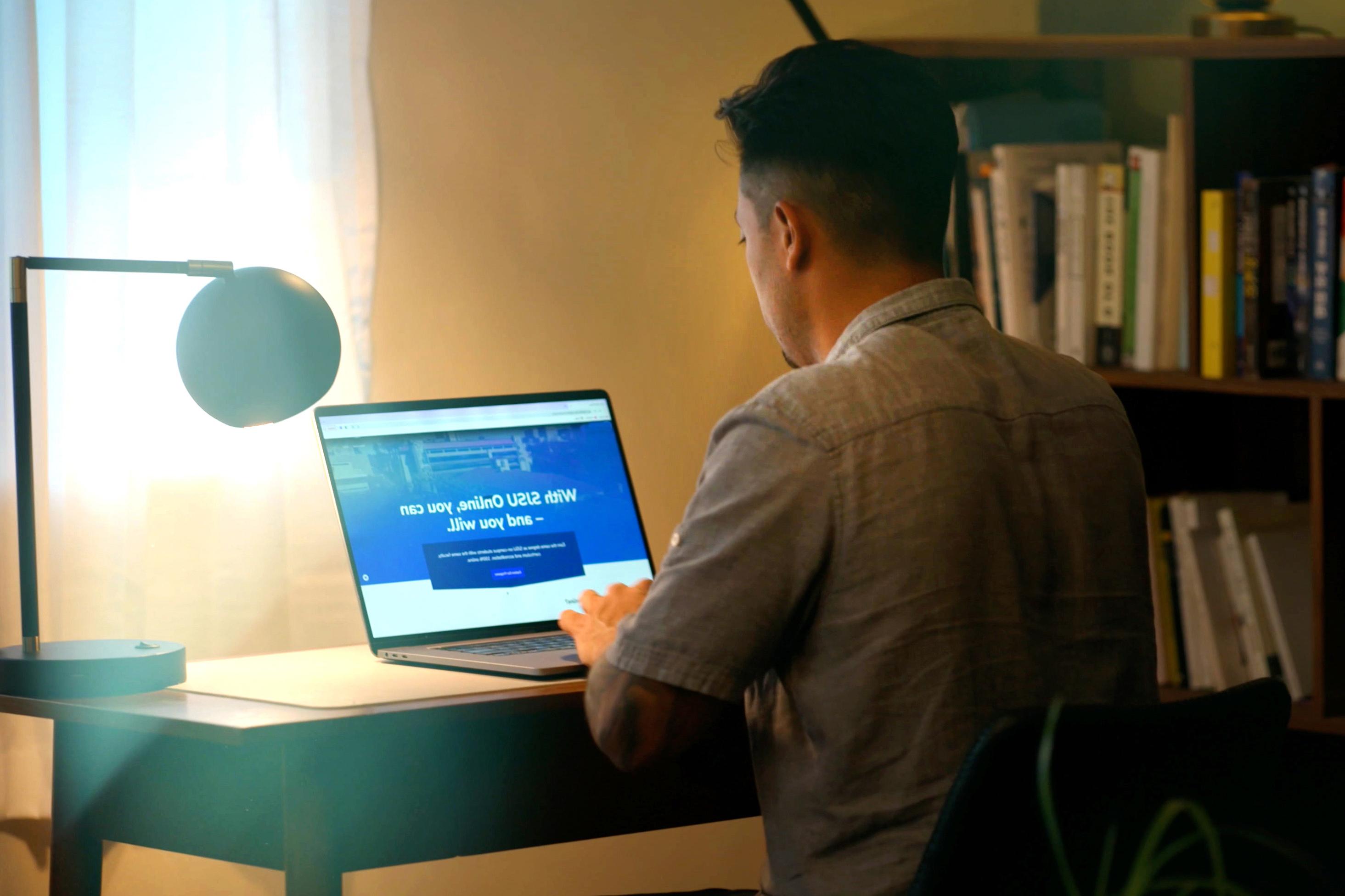 Man looking at the 菠菜网lol正规平台 Online homepage on his laptop.